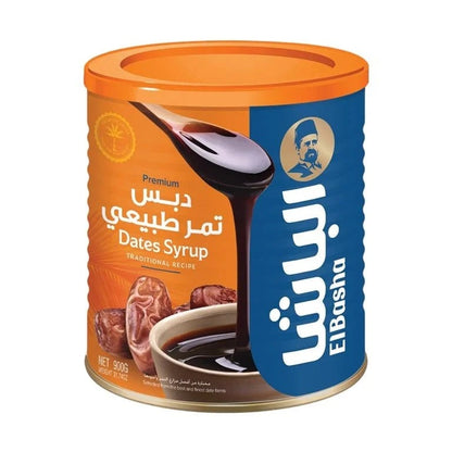 EL Basha Date Syrup 900g in metal can with orange lid, traditional recipe label, and dark brown syrup dripping from wooden spoon
