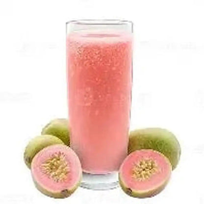 Frothy pink guava juice in glass with visible pulp particles surrounded by fresh green guavas