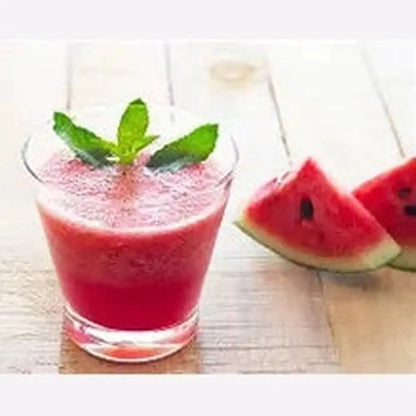 Frosted glass of deep red watermelon drink with mint garnish and fresh fruit wedges on wood