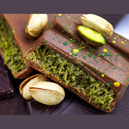broken dark chocolate bar revealing green shredded pistachio cream filling with edible speckles on glossy shell