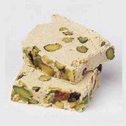 Close-up cross-section of Hana Halawa with Pistachio showing dense beige sesame confection texture with chopped green pistachios and dried fruit bits