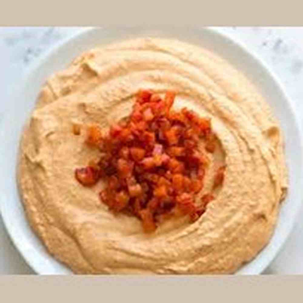 Creamy Hana hummus dip swirled in bowl with diced tomato and onion