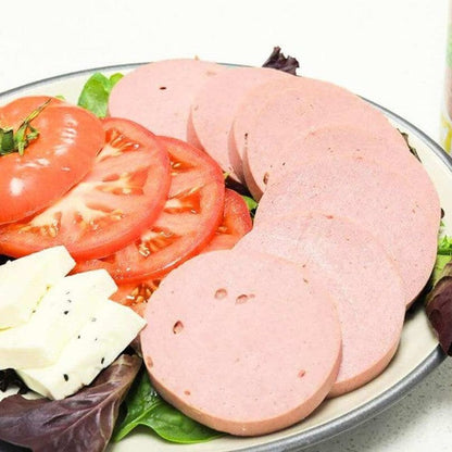 sliced pink halal beef luncheon meat with lettuce tomato and cheese on white plate
