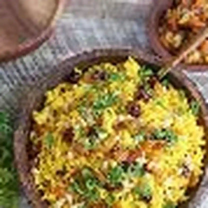 Golden yellow kabseh rice with meat and herbs in rustic clay bowl