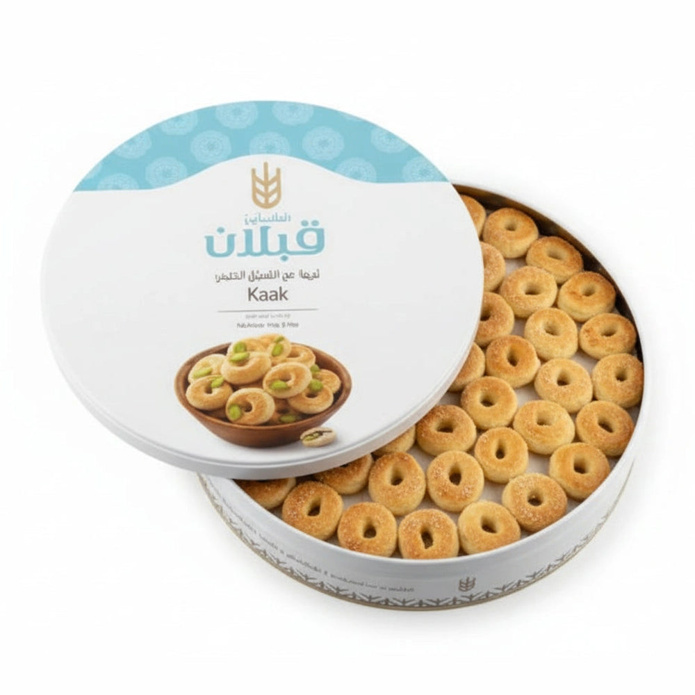 Qabalan Super Graibeh pistachio cookies in white tin with blue lid, golden ring-shaped Syrian sweets with sugared surface and green pistachio garnish